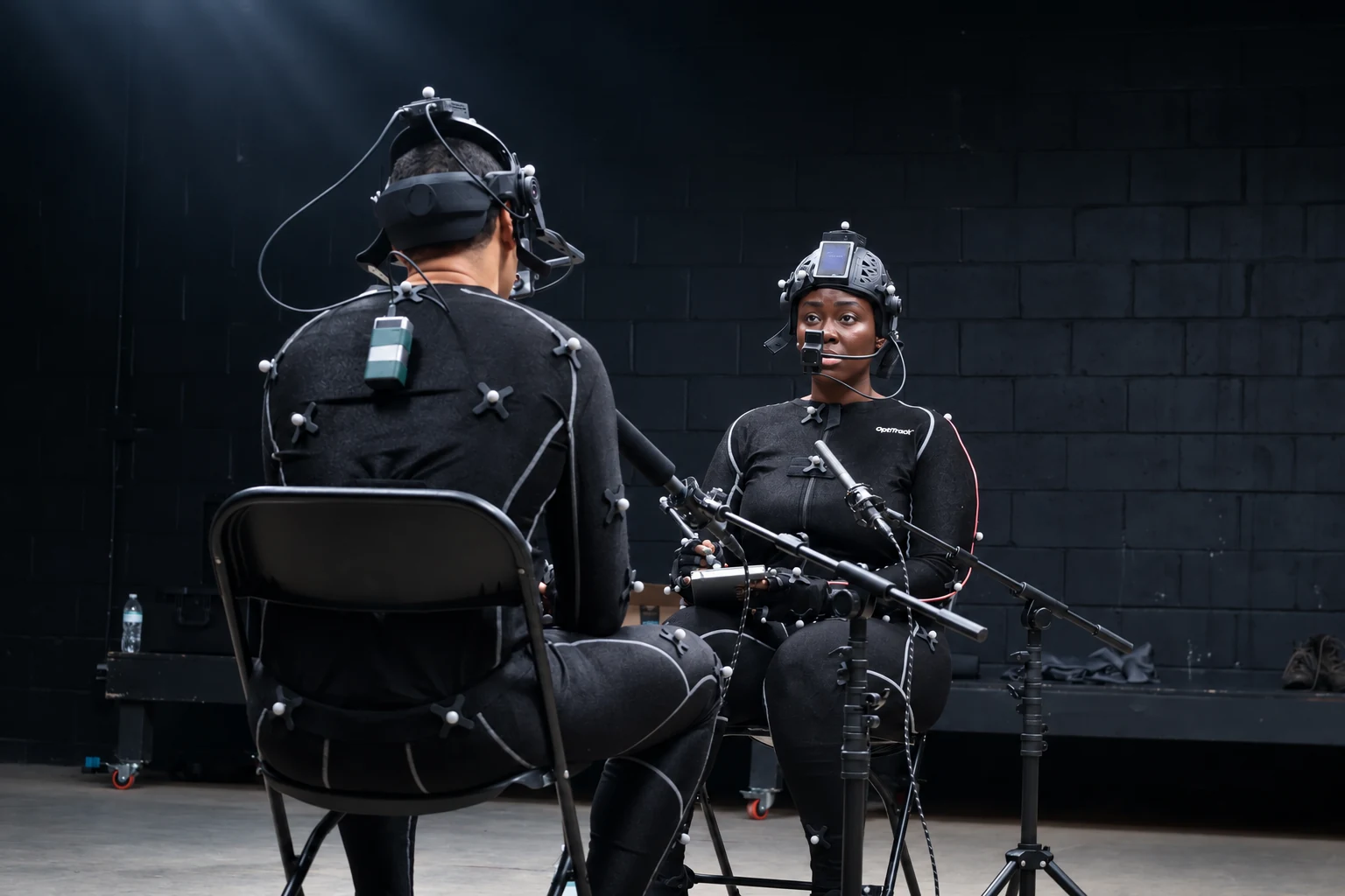 Reverse angle of the Recall performance capture session showing the actor’s facial headset, body markers, and microphones