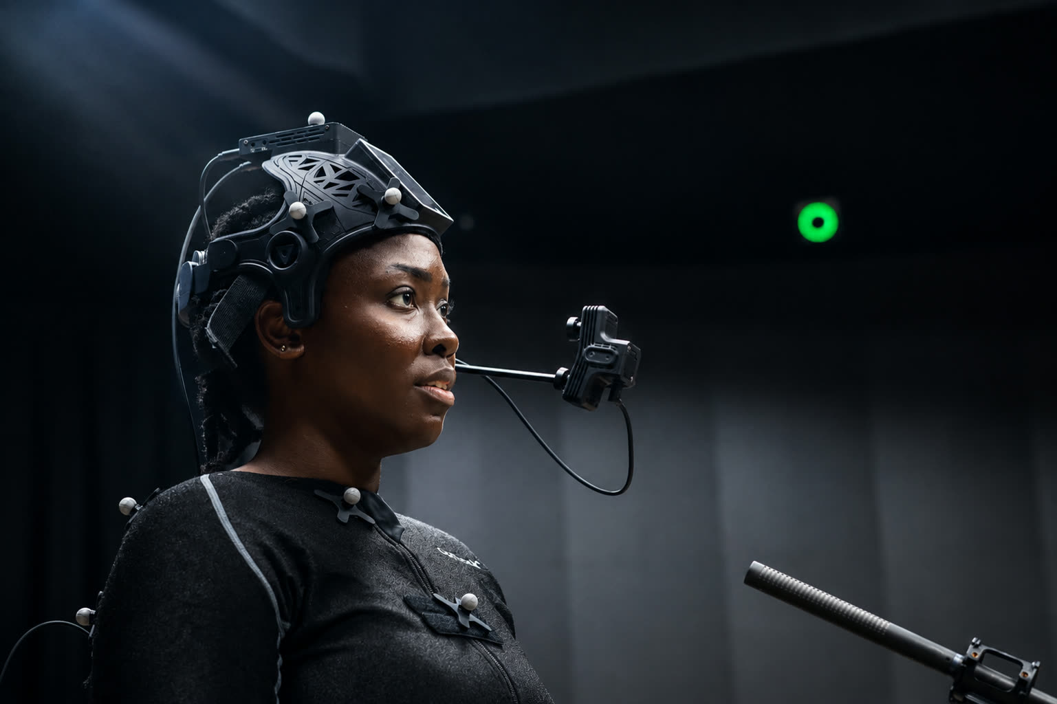 Performer wearing stereoscopic head-mounted camera with chest markers in low-light studio