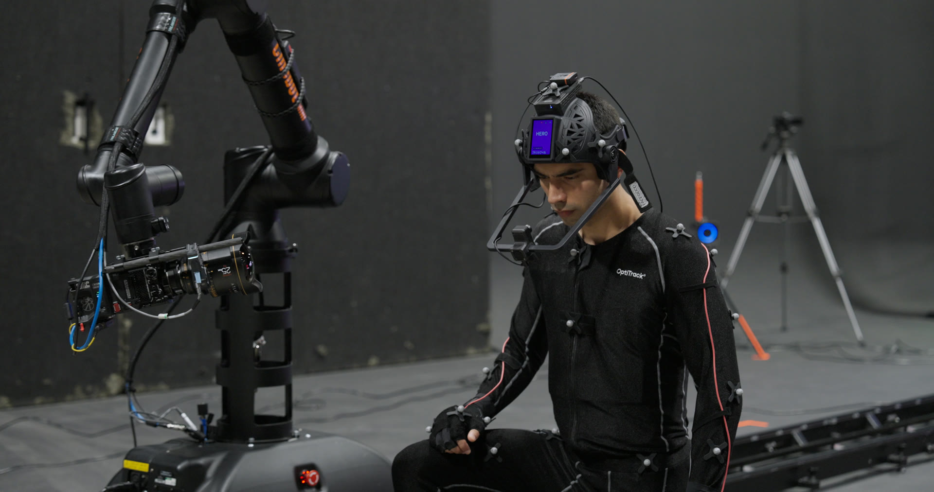 Performance capture session at the Form Studios Atlanta stage — performer in an OptiTrack motion capture suit with head-mounted facial camera beside the 6-axis cinema robot